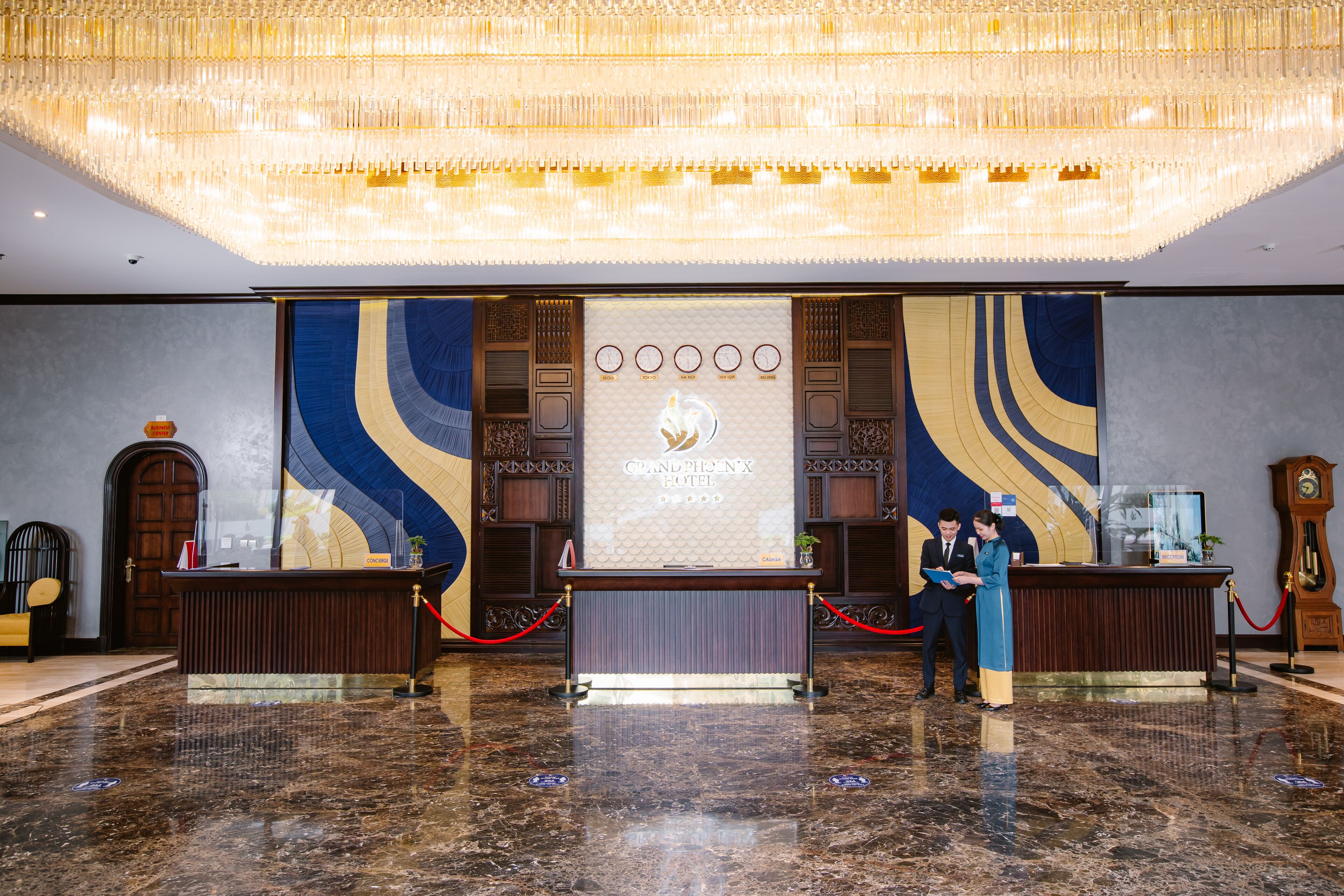 Ein Hotel-Empfangsbereich mit Marmorboden, einem großen Kronleuchter und einem Empfangstresen.