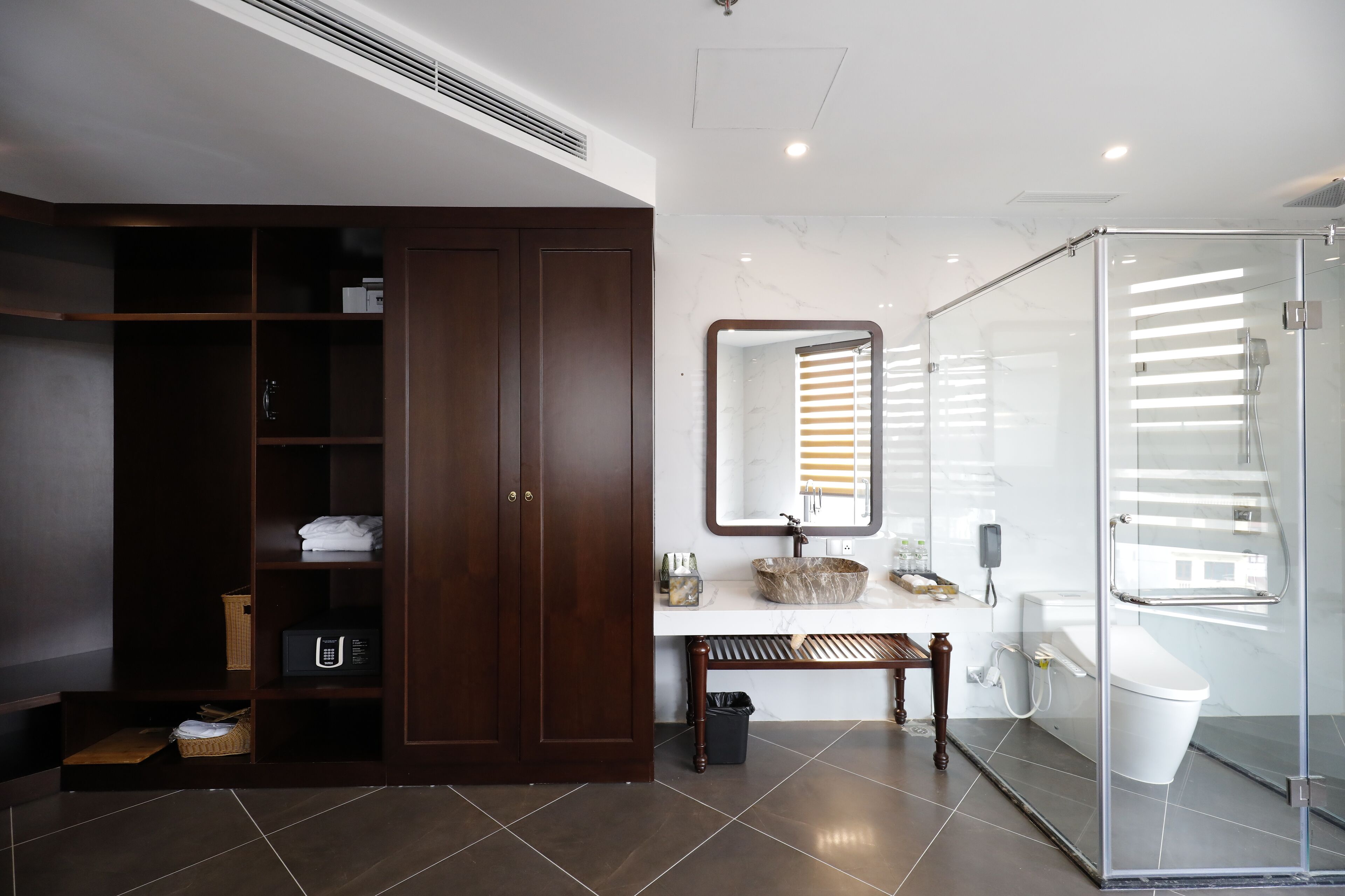 A modern bathroom with a walk-in shower, a large mirror, and a vanity with a marble countertop.