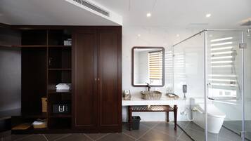 A modern bathroom with a walk-in shower, a large mirror, and a vanity with a marble countertop.