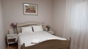 Een slaapkamer met een bed, nachtkastjes, een schilderij en een gordijn.