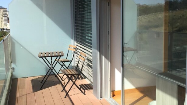 A balcony with a wooden floor, a small table, and two chairs.