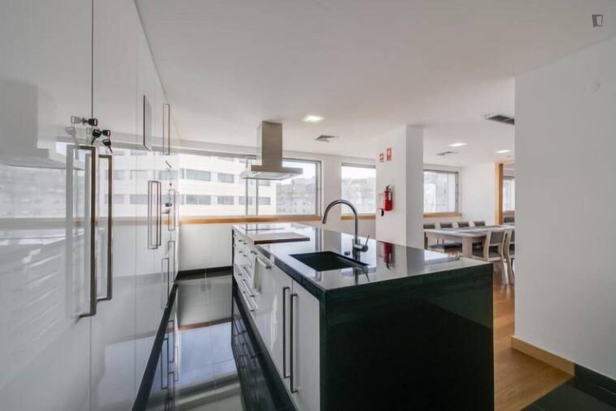 Una cocina moderna con una isla central, electrodomésticos de acero inoxidable y un amplio ventanal que proporciona luz natural.