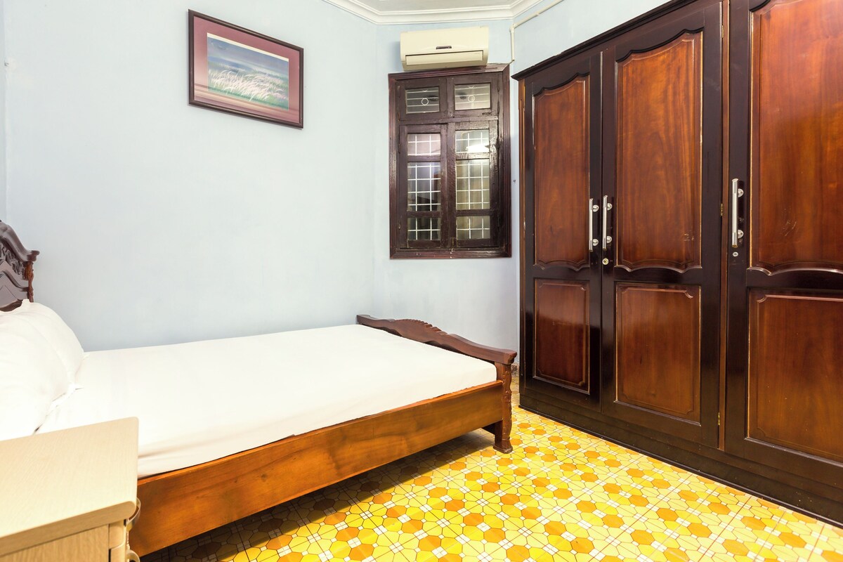 A bedroom with a bed, wardrobe, and a framed picture on the wall.
