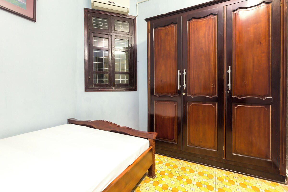 A bedroom with a bed, wardrobe, and window.