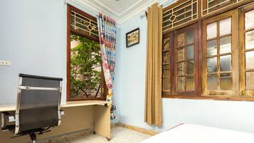 A room with a desk, office chair, and a window with curtains.