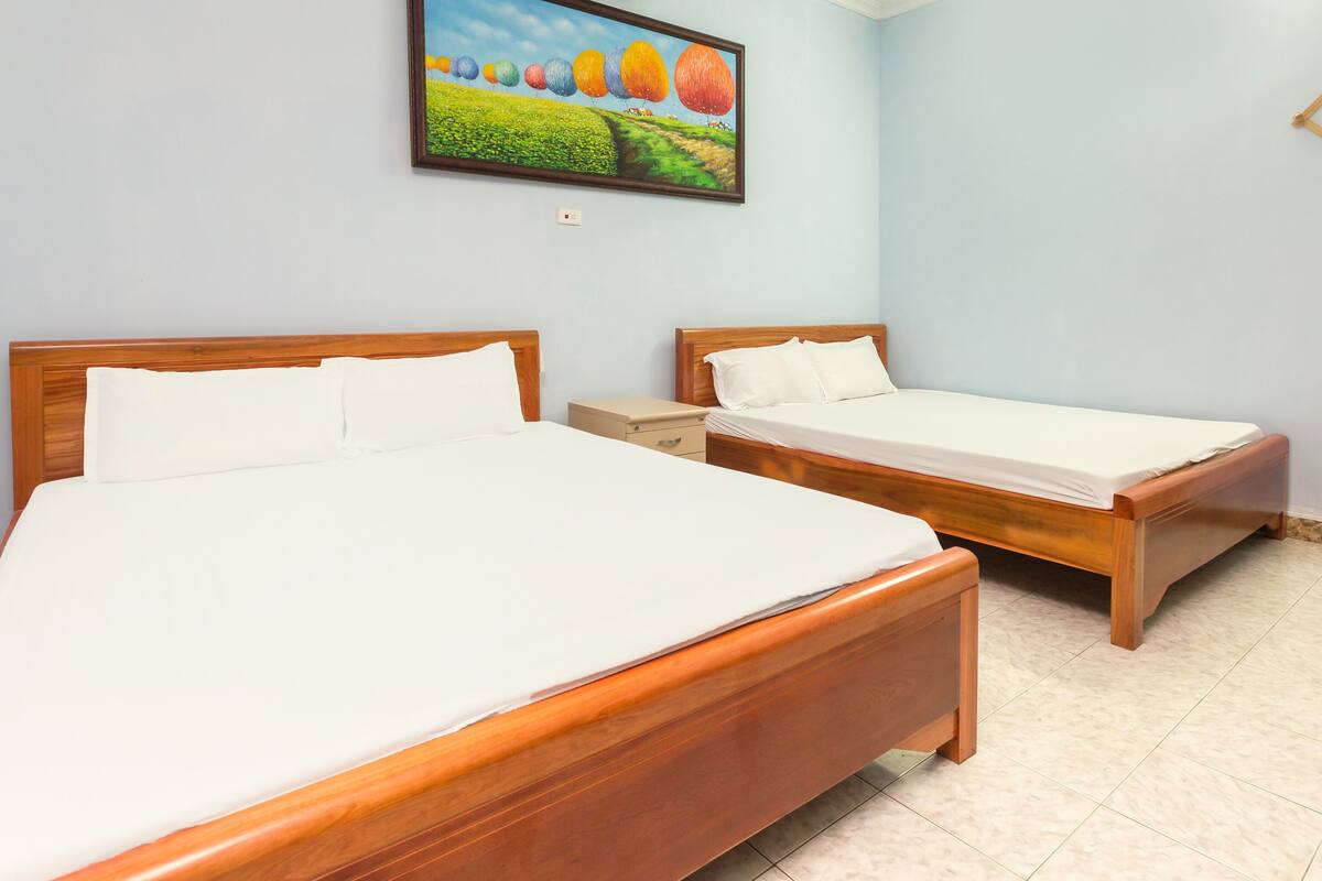 A hotel room with two wooden beds, a nightstand, and a painting of colorful balloons on the wall.