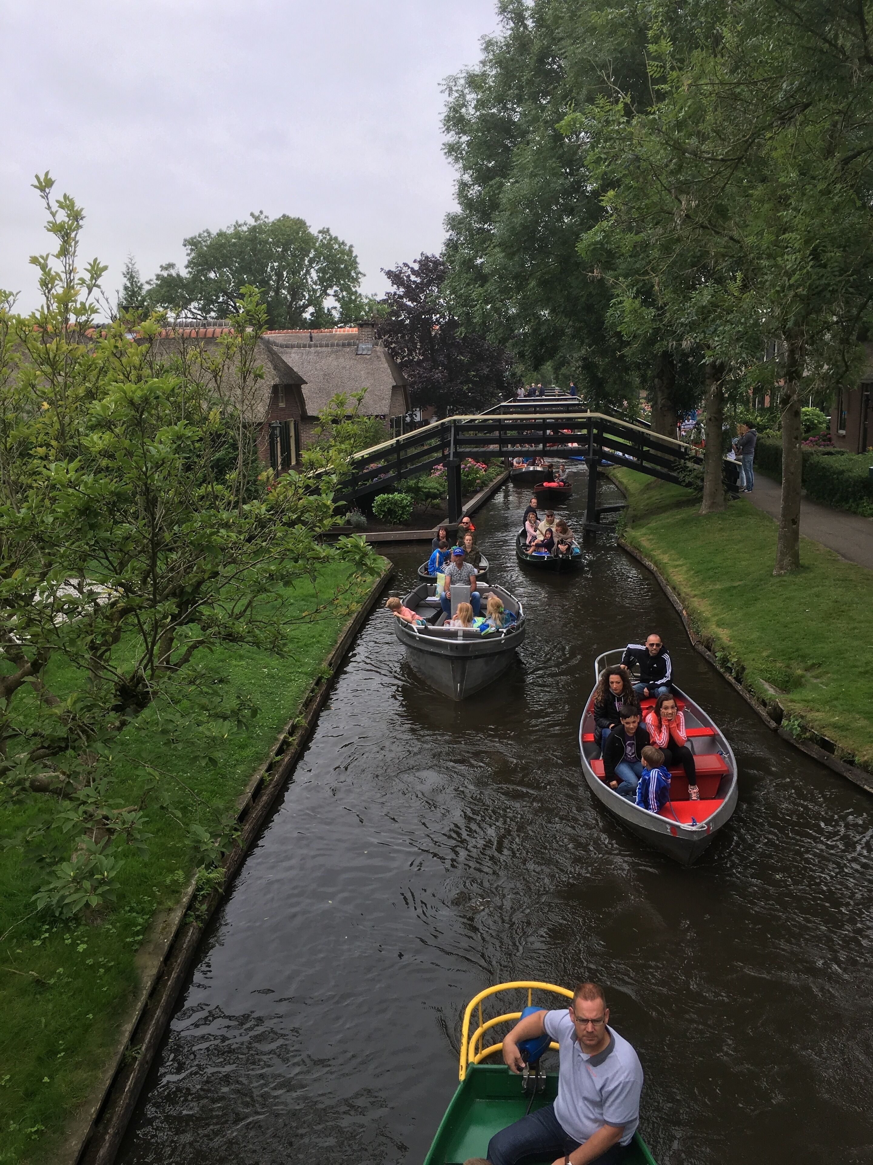 Ein Kanal mit Booten, einer Brücke und viel Grün.