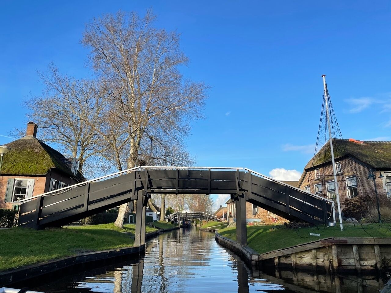 Un canal surmonté d’un pont, avec des bâtiments de chaque côté, et un ciel bleu dégagé.