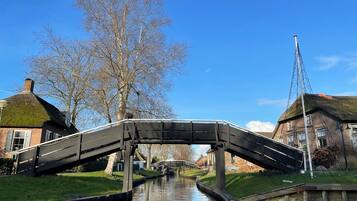 Een gracht met een bruggetje, gebouwen aan beide zijden en een heldere blauwe lucht.