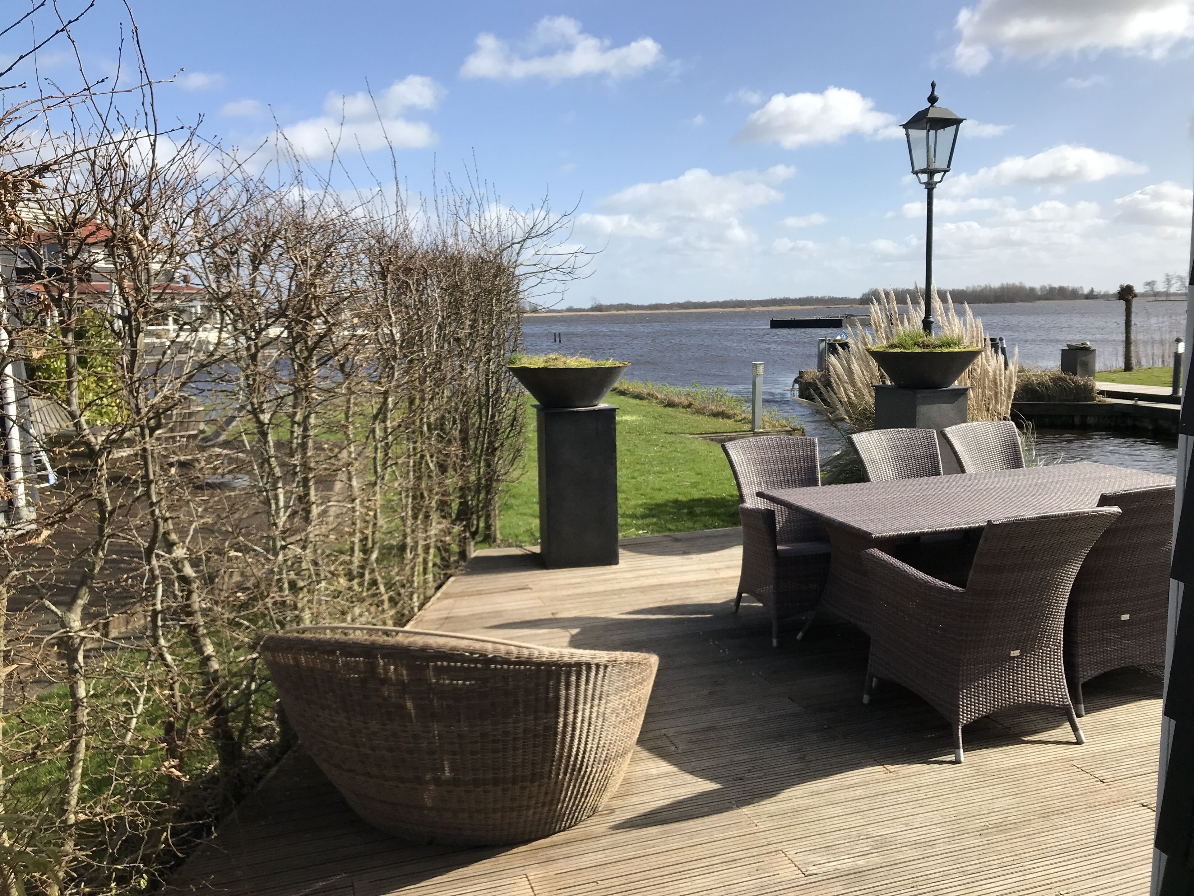 An outdoor patio with wicker furniture, a view of a body of water, and a lamp post.