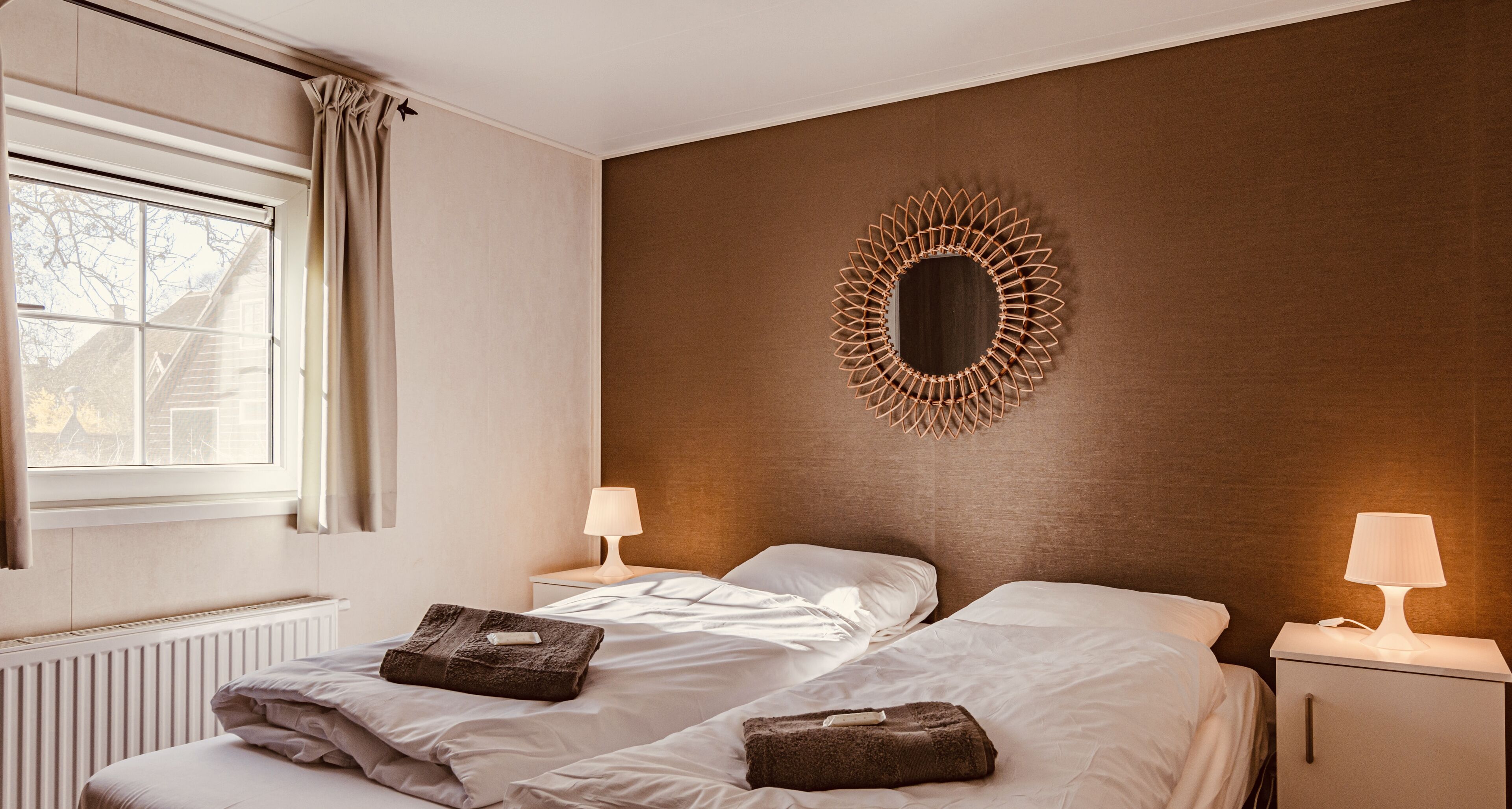 A hotel room with two beds, a large mirror, and two bedside lamps.