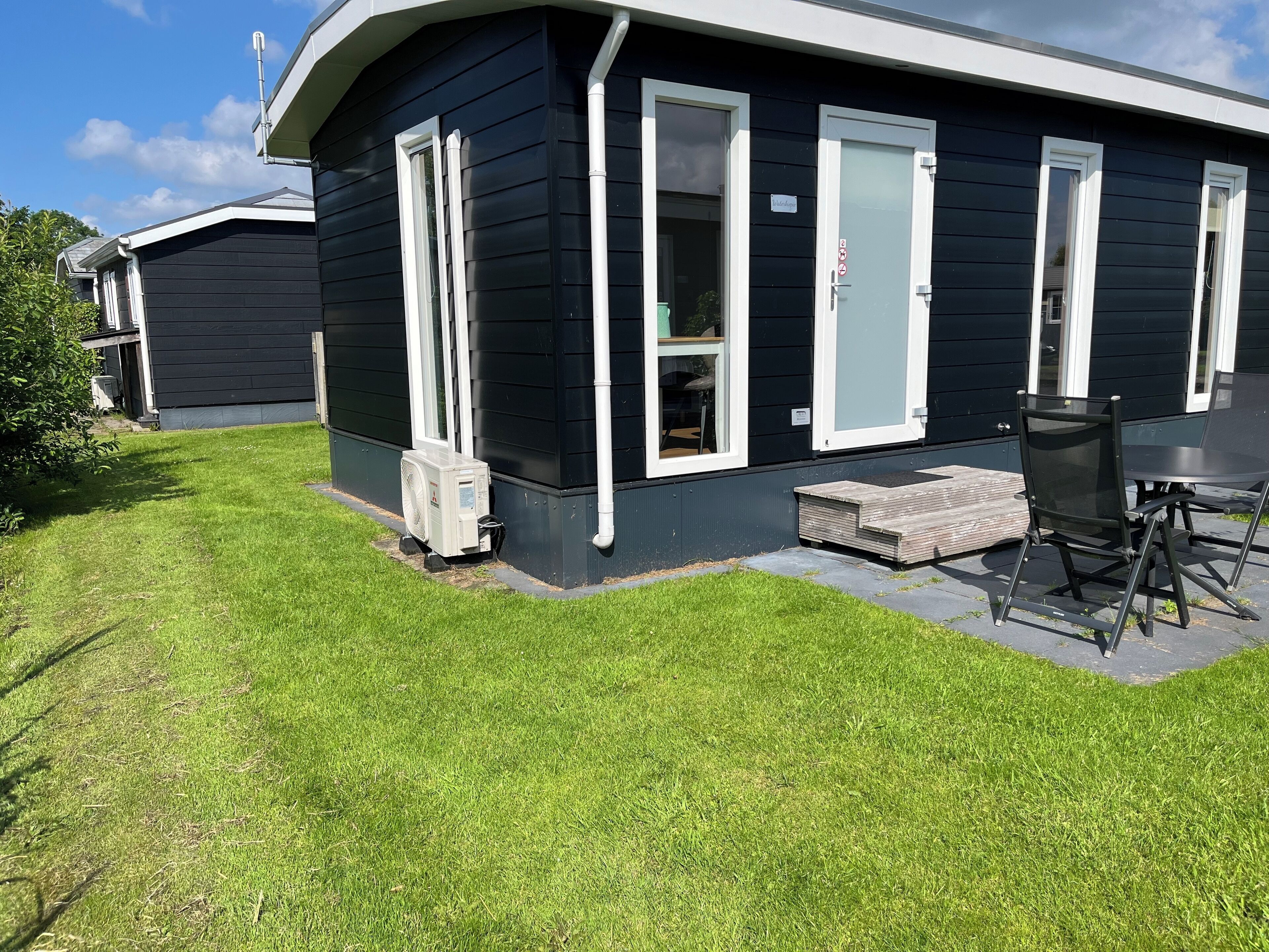 A black house with white trim, a small porch, and a table with chairs.