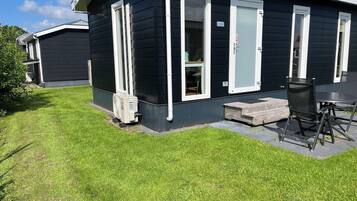 A black house with white trim, a small porch, and a table with chairs.