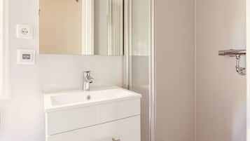Een badkamer met een wit wastafel, een spiegel en een deur.