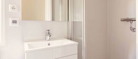 Une salle de bain avec un lavabo blanc, un miroir et une porte.