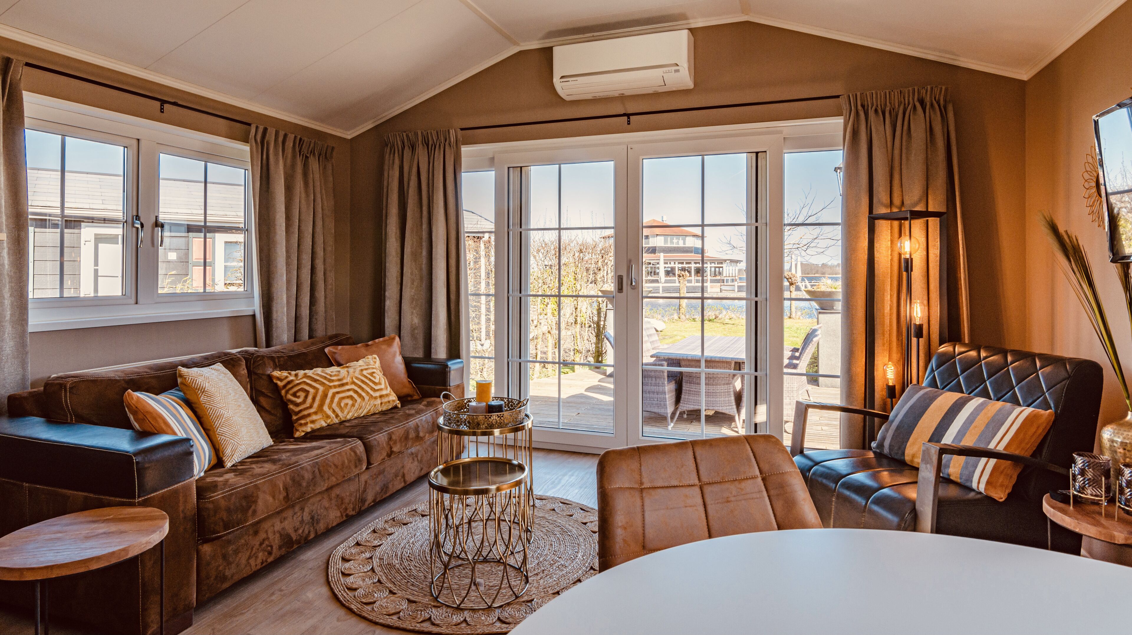 A cozy living room with a brown leather sofa, a round coffee table, and a dining table.