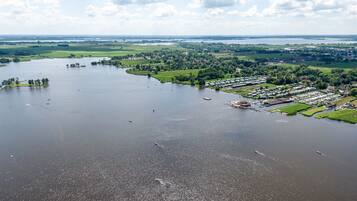An aerial view of a riverside area with a marina, green fields, and residential buildings.