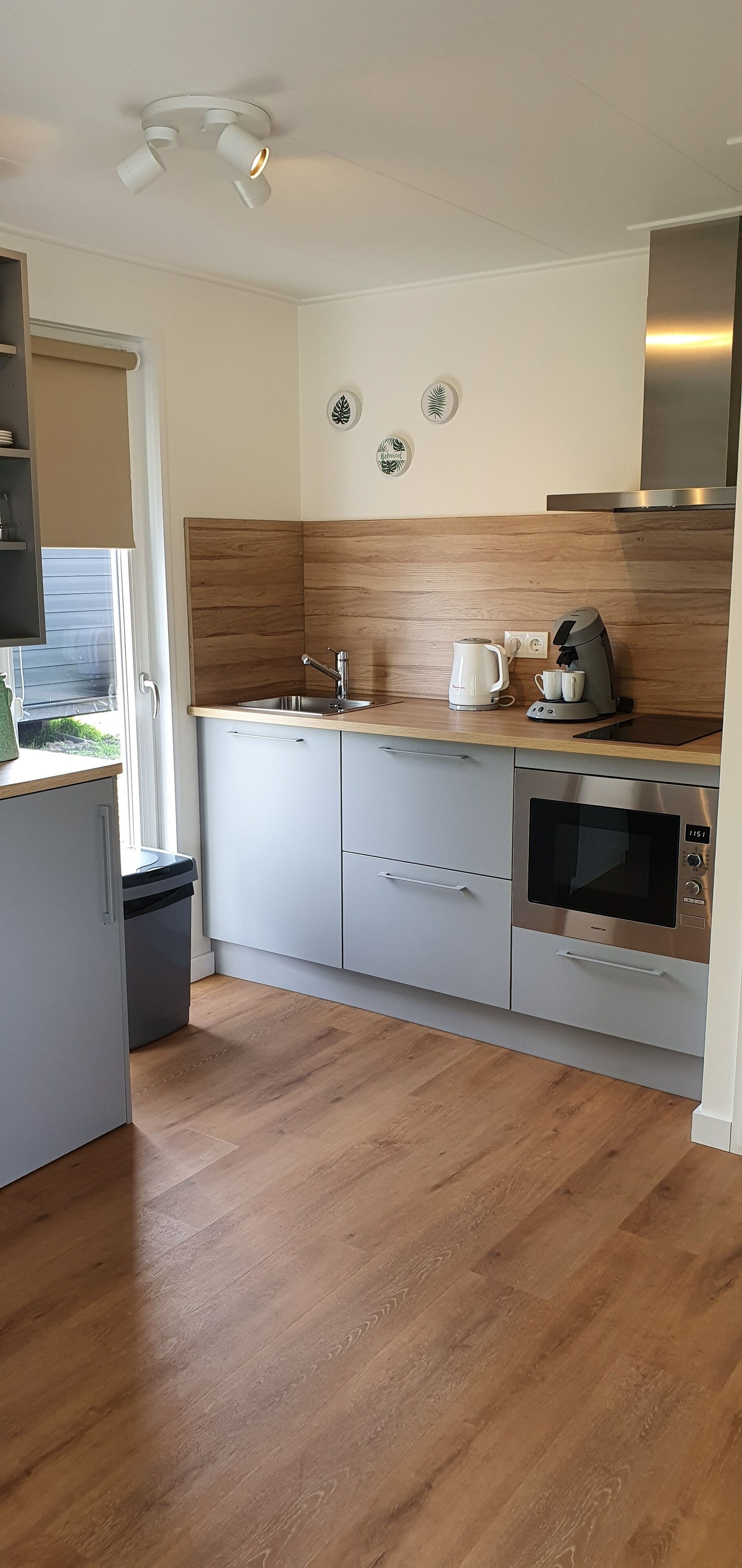A modern kitchen with a stainless steel oven, a coffee maker, and a sink.
