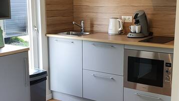 A modern kitchen with a stainless steel oven, a coffee maker, and a sink.