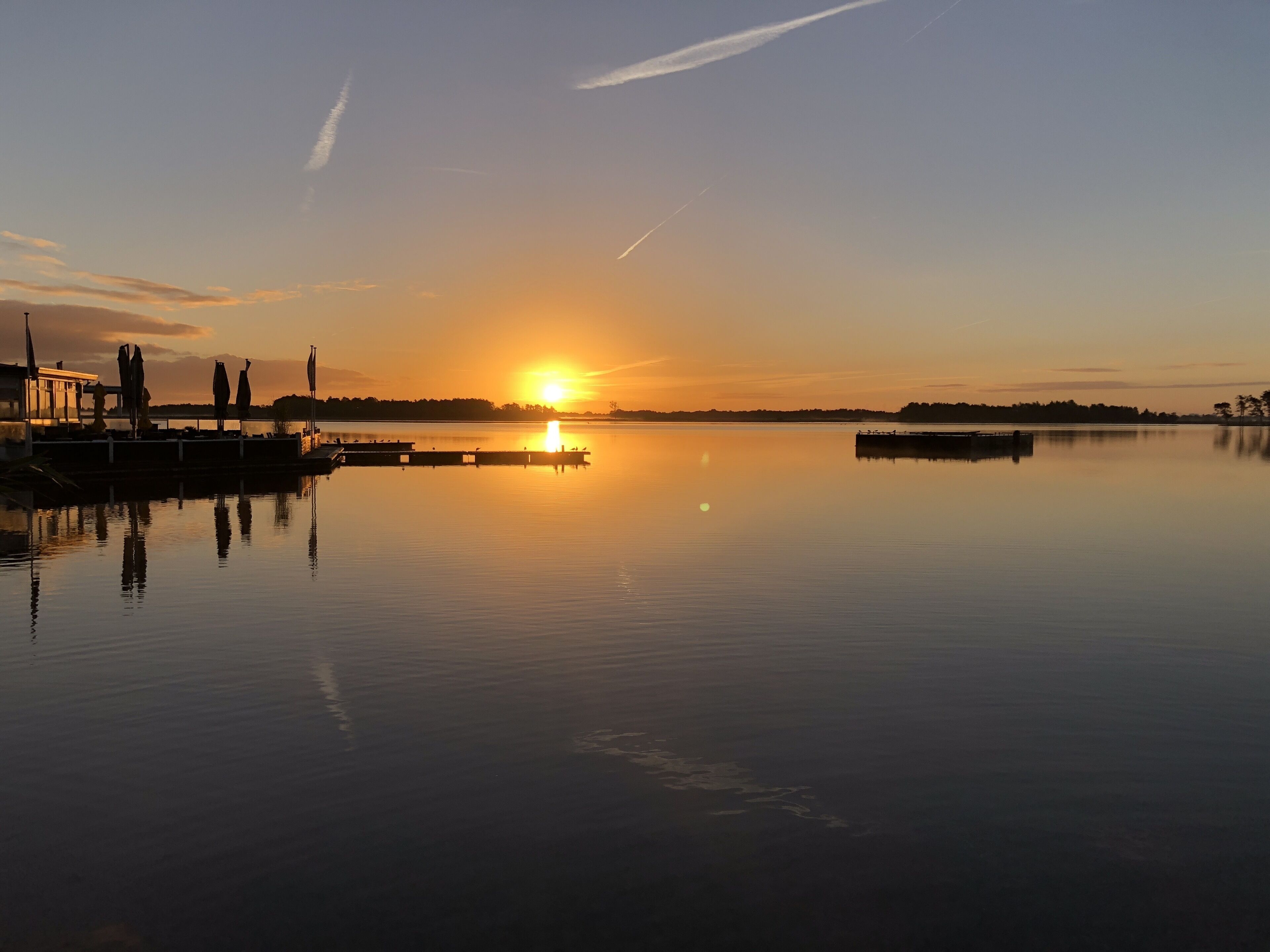 Un lago tranquilo al atardecer con un muelle que se adentra en el agua.
