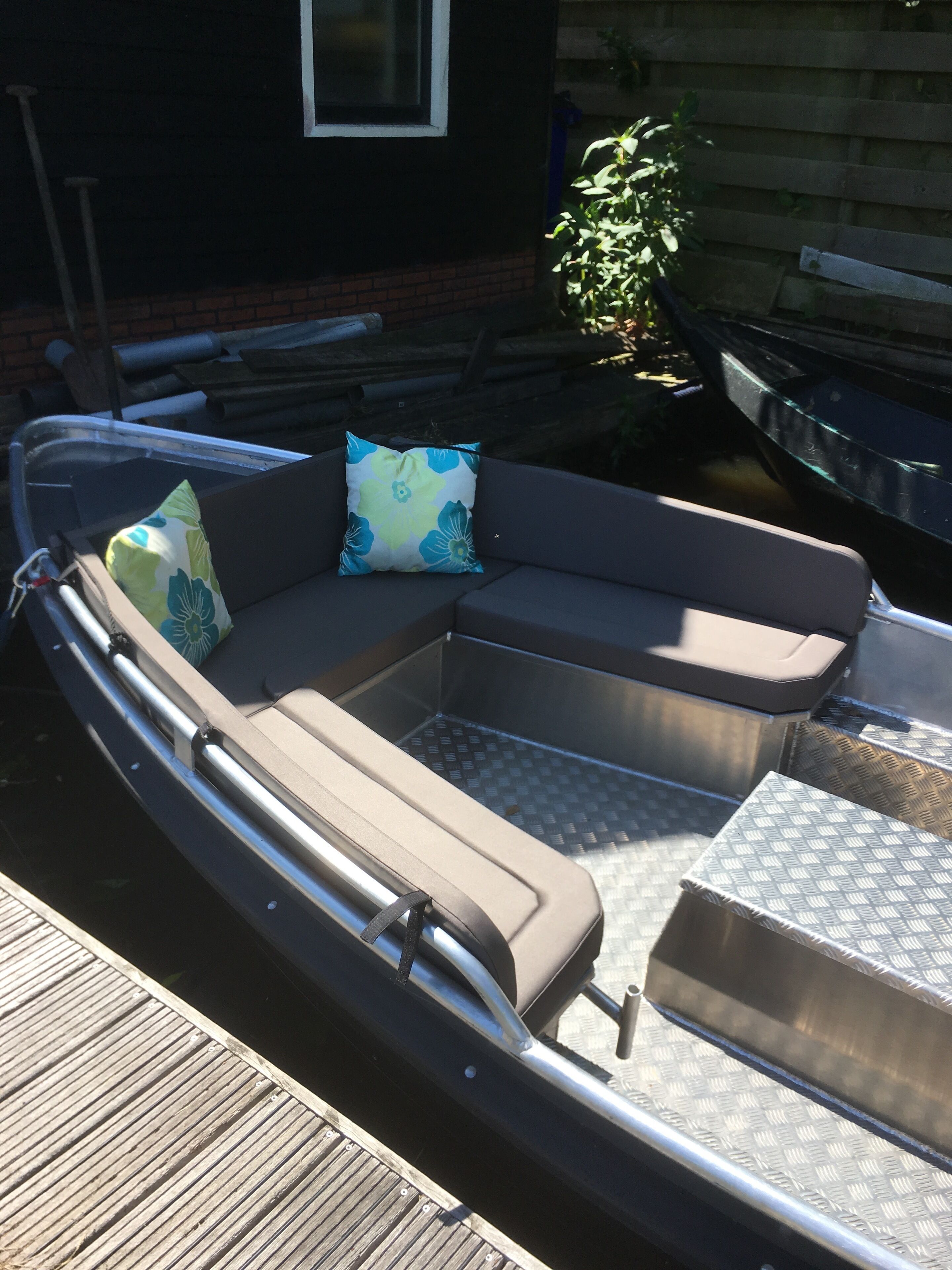 A boat-shaped outdoor seating area with a cushioned bench and metal railings.