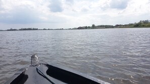 A river with a boat in the foreground and buildings on the opposite bank. - Kroondomein Giethoorn (Giethoorn)