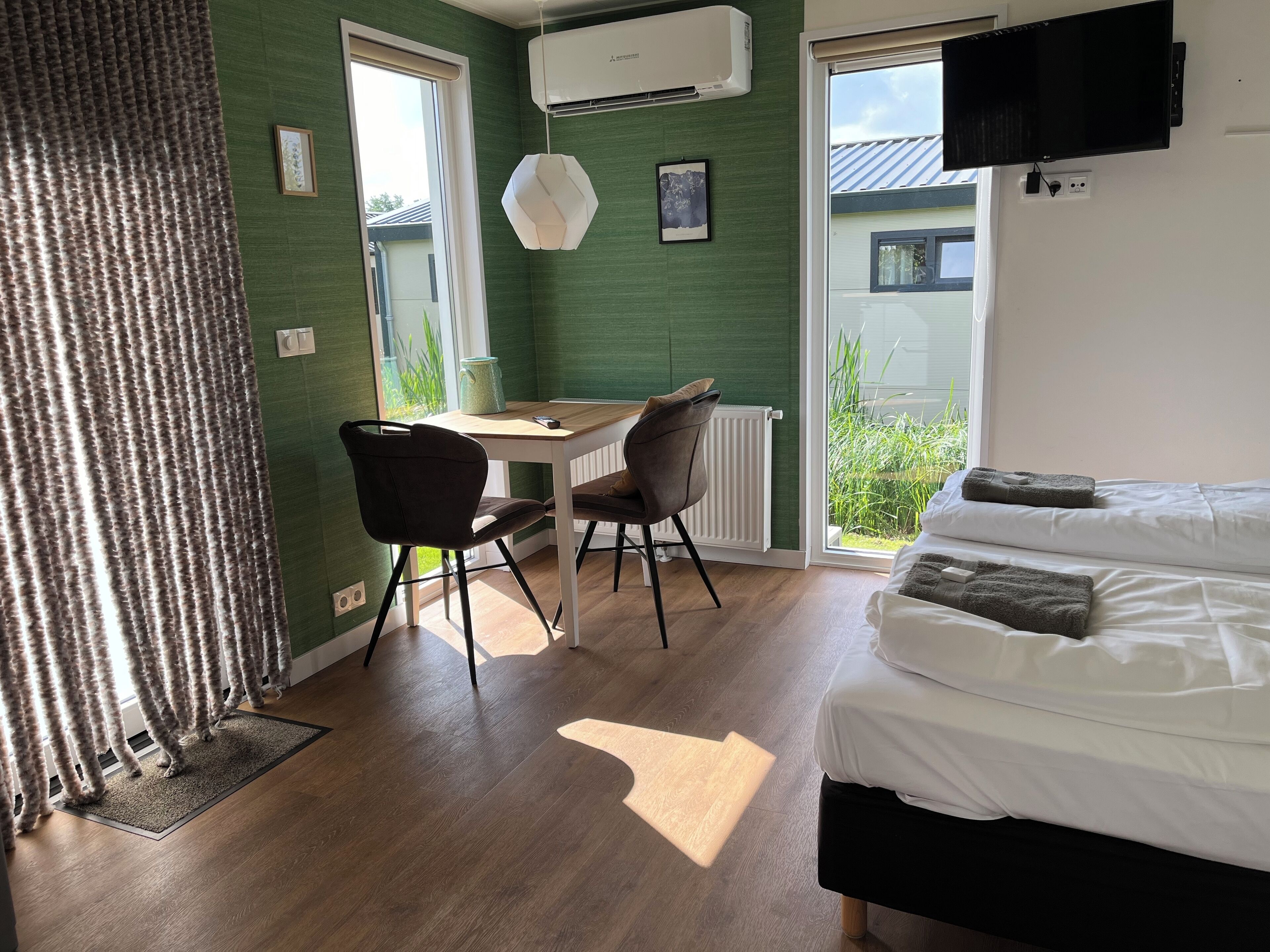 Una habitación con cama, escritorio y sillas. Hay una ventana con vista a áreas verdes.