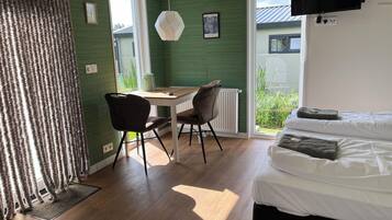 Una habitación con cama, escritorio y sillas. Hay una ventana con vista a áreas verdes.