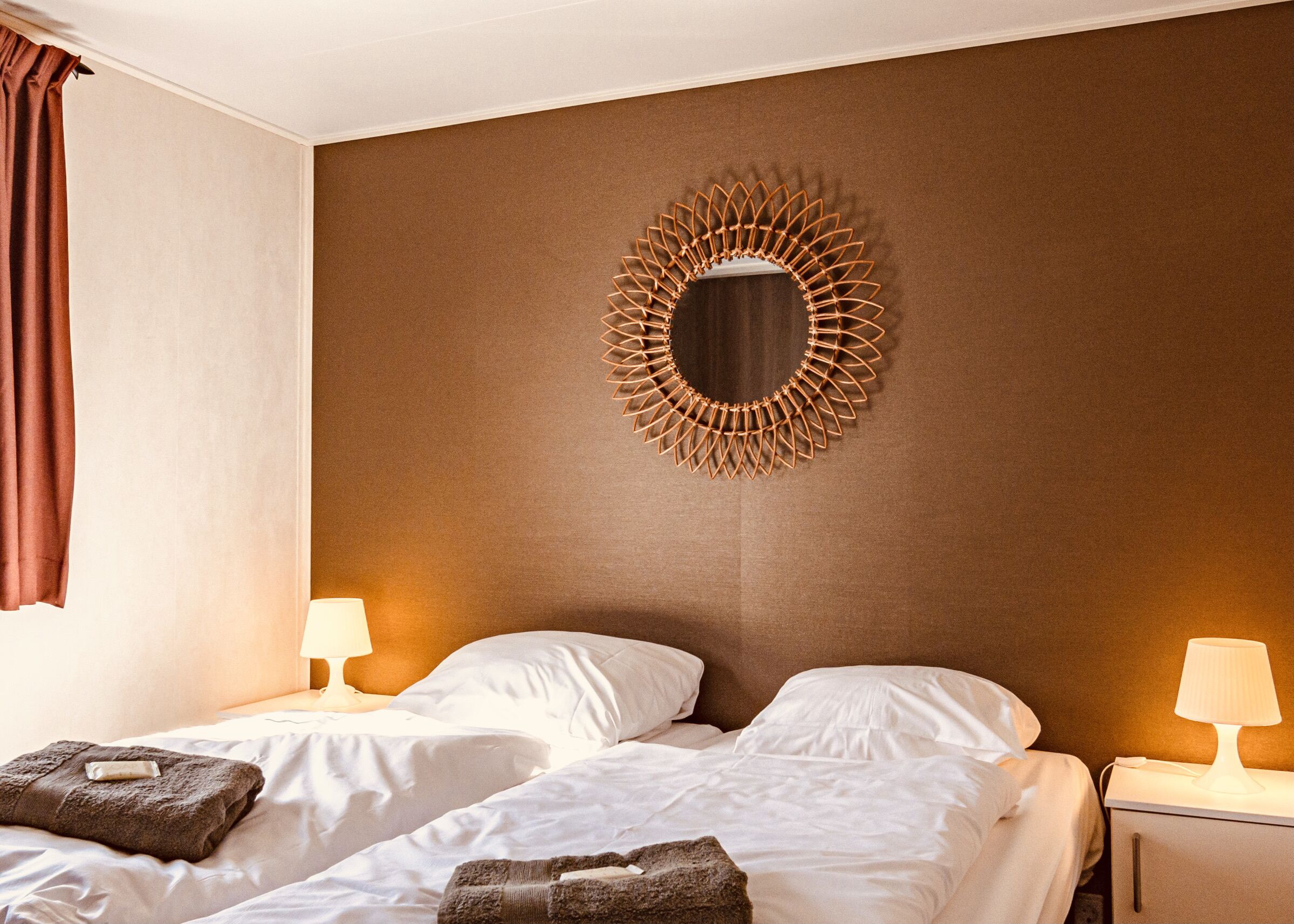 Habitación de hotel con dos camas, un espejo decorativo y lámparas de noche.