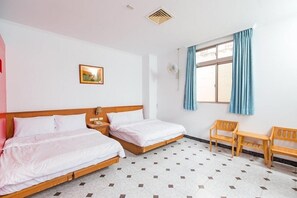 Habitación de hotel con dos camas individuales, una mesita, dos sillas, un ventanal con cortinas y un cuadro en la pared.