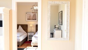A bedroom with a bed, bedside table, lamp, and a mirror on the wall. - 4-room apartment with balcony - Villa Park Ocean (Scharbeutz)