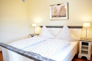 A neatly made bed with a floral bedspread, two bedside lamps, and a framed picture on the wall.