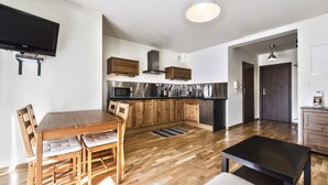 A modern kitchen with wooden cabinets, a built-in oven, and a stainless steel refrigerator. - Apartamenty Sun&Snow Kościelisko Chotarz (Koscielisko)