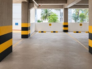 Un parking souterrain vide, avec des piliers en béton et des barrières rayées de jaune et de noir.