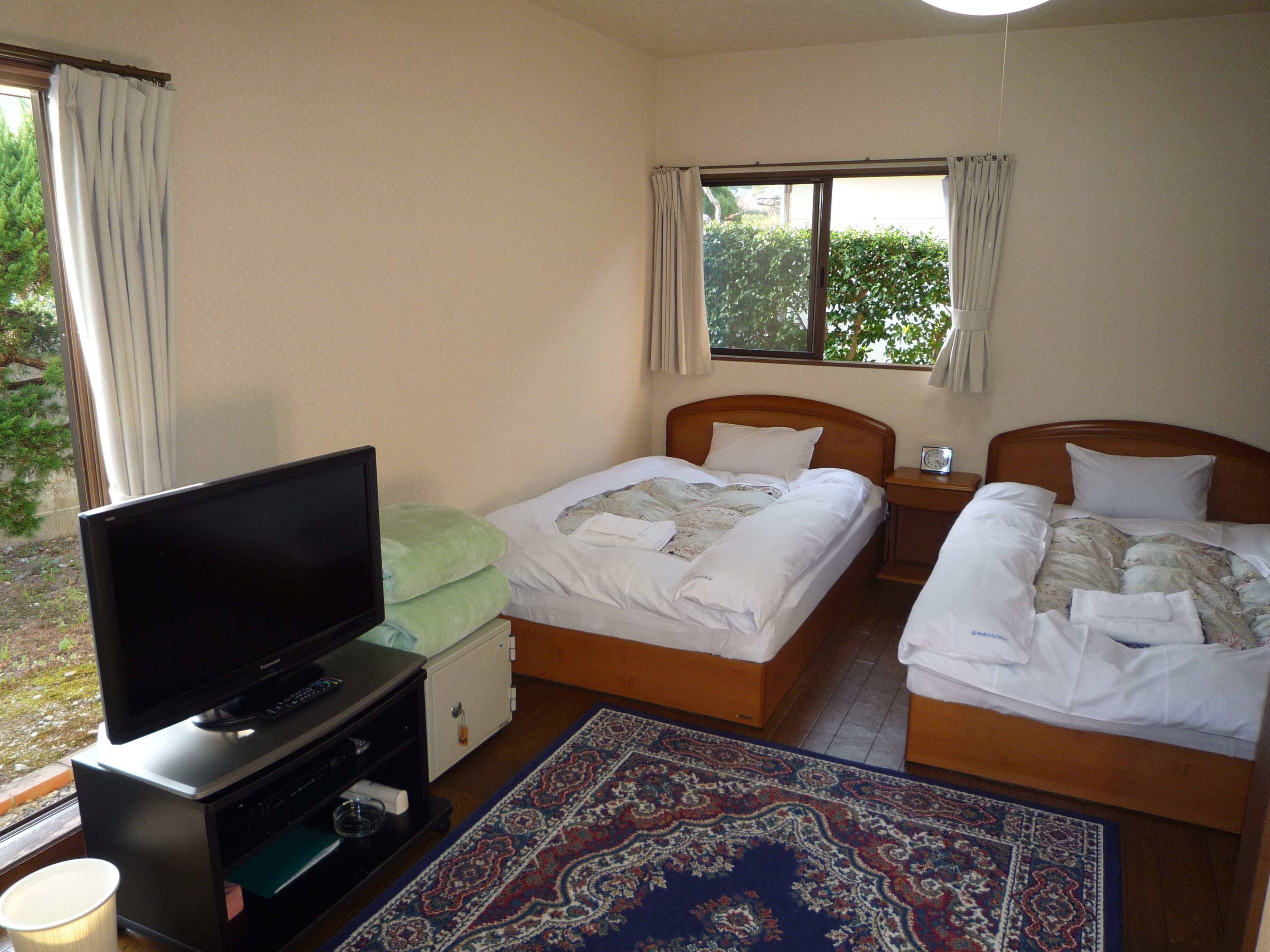 A hotel room with two beds, a television, a small table, and a window with curtains.