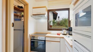 Una cocina compacta con horno empotrado, refrigerador y ventana con vista a un jardín.