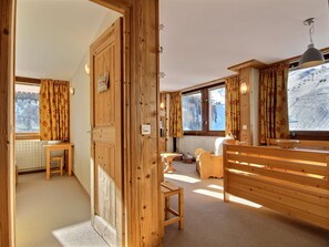 A cozy room with wooden walls and furniture, a window with a view of a snowy landscape, and a radiator under the window. - Bright 3-Bedroom Apartment for 6 at the Foot of the Slopes (La Plagne)