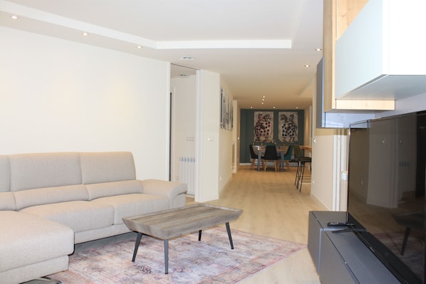 A modern living room with a sofa, a coffee table, and a flat-screen TV.