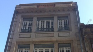 Un edificio de varios pisos con amplios ventanales y barandillas de hierro decorativas.