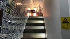 Una escalera con baldosas azules estampadas en las paredes, una barandilla y un cartel de advertencia en la pared.