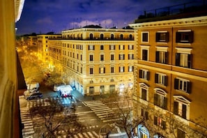 Une vue nocturne d’une rue de la ville, avec des immeubles, un passage piéton et quelques véhicules.