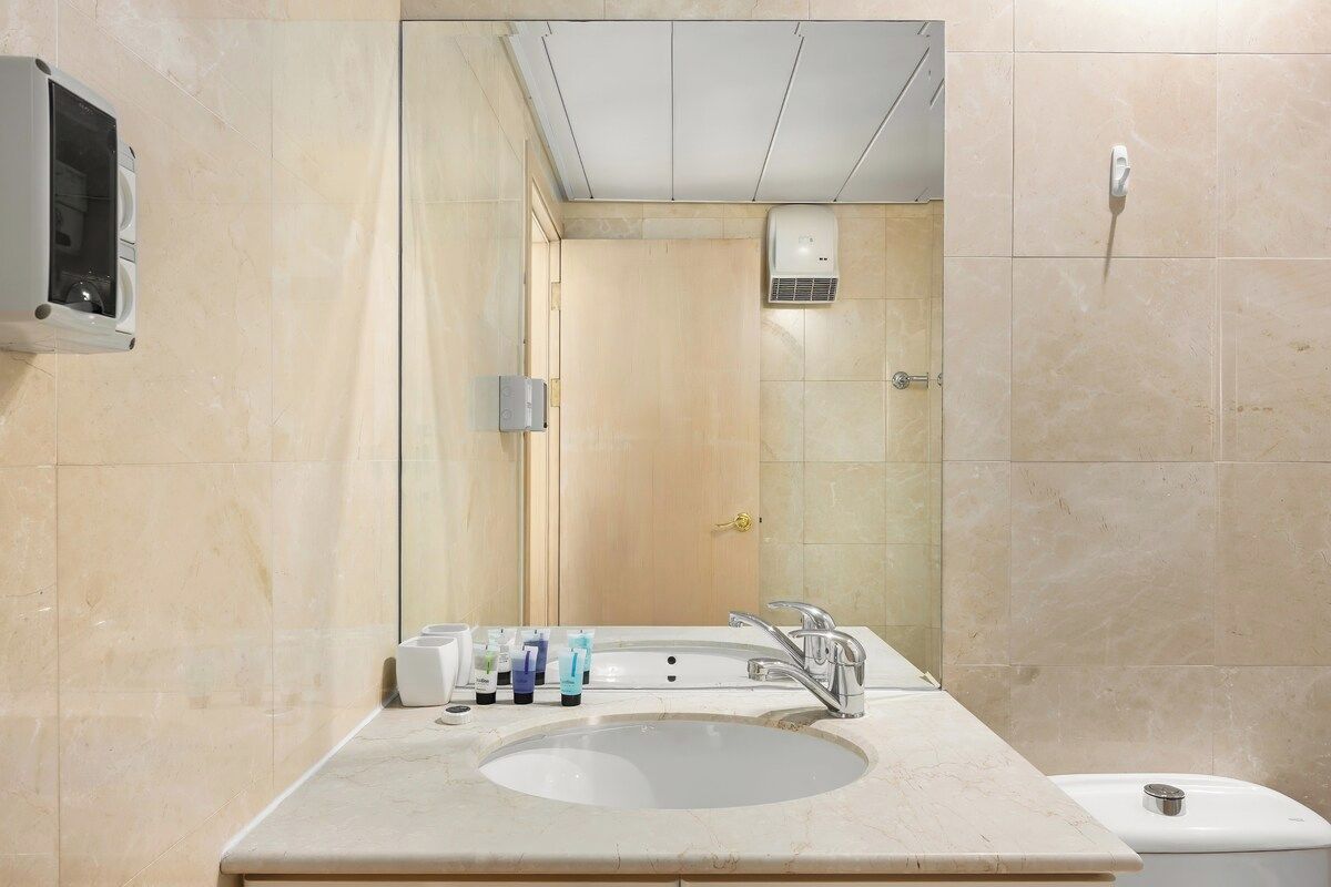 A modern bathroom with a large sink, mirror, and a toilet.