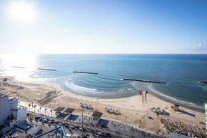 Une vue côtière avec une plage, l’océan et une jetée qui s’avance dans l’eau.