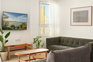 Ein Wohnzimmer mit einer Couch, einem Tisch, einer Bank und einer Topfpflanze.