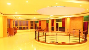 Un vestíbulo amplio con una barandilla circular central, ventanas grandes y un techo luminoso y bien iluminado.