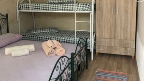 Een slaapkamer met een stapelbed, een houten garderobe en een klein vloerkleed.