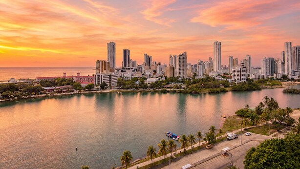 Un paisaje urbano con rascacielos, una zona costera y un cielo al atardecer.