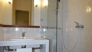 Un baño con cabina de ducha de vidrio, un lavabo blanco y un espejo con luces empotradas.
