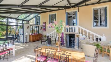 A spacious living area with a wooden dining table, chairs, and a staircase leading to an upper floor.