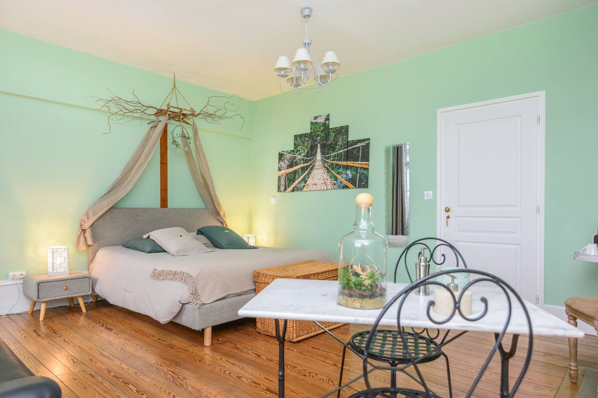 A bedroom with a bed, bedside table, lamp, and a wall-mounted artwork.
